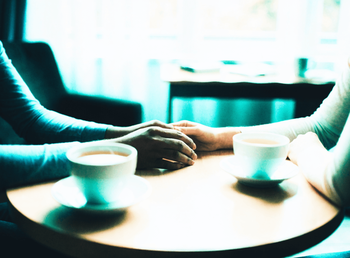Two people sharing tea across a table in a calm therapy room